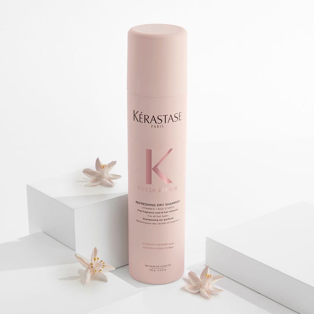 A bottle of Kérastase hair spray is sitting on top of a white cube