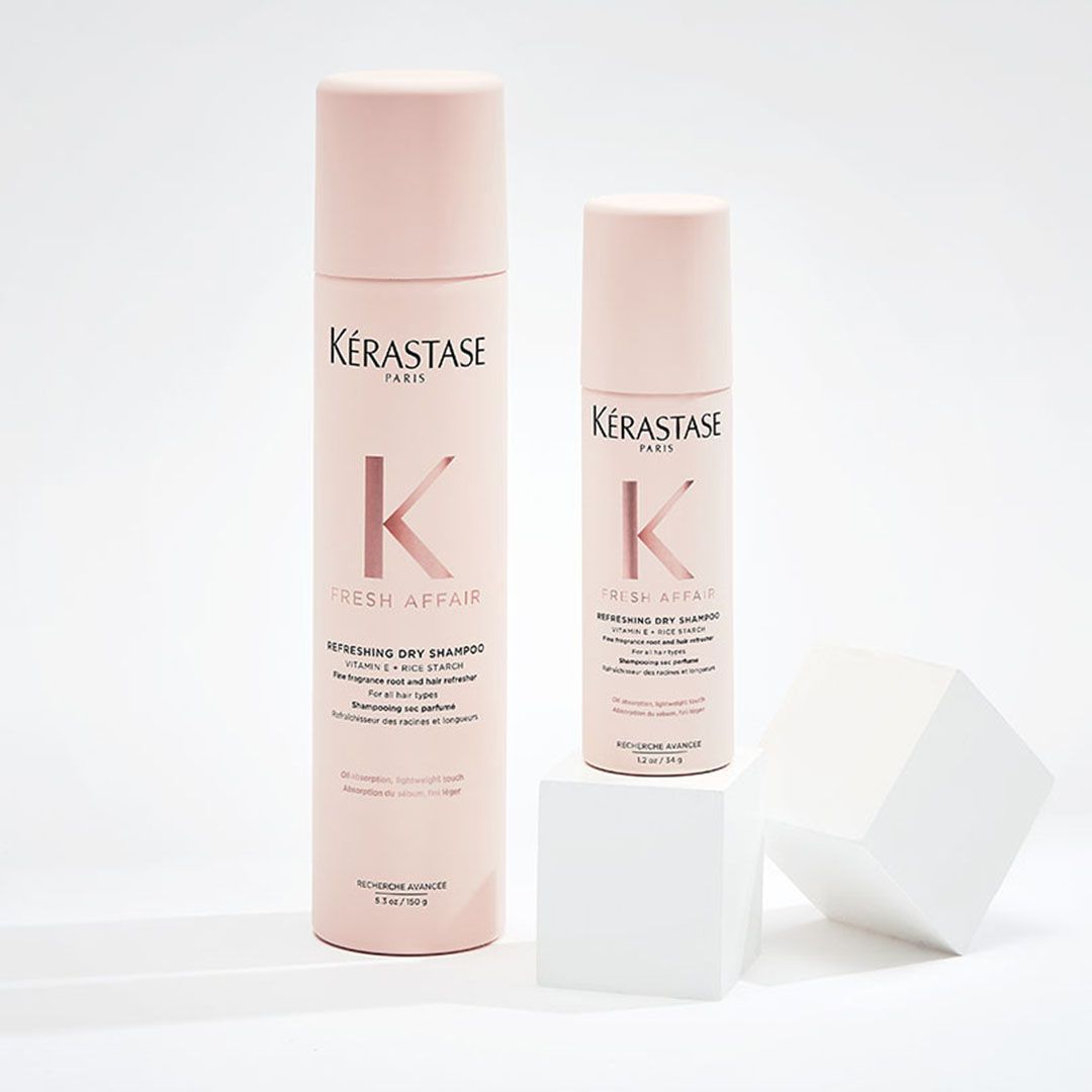 Two bottles of Kérastase hair products are sitting on a white cube