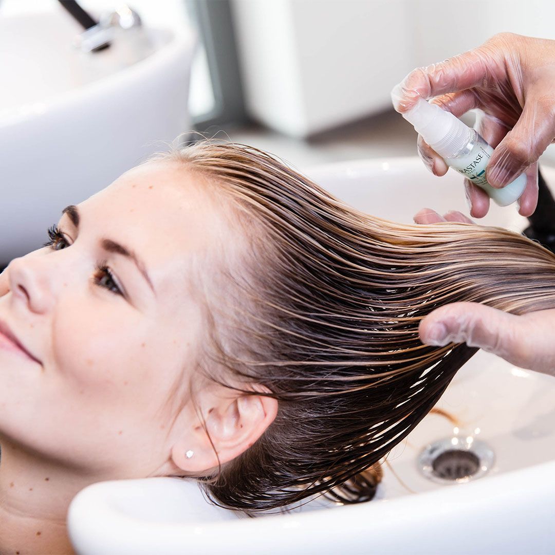 A woman is getting her hair washed in a sink
