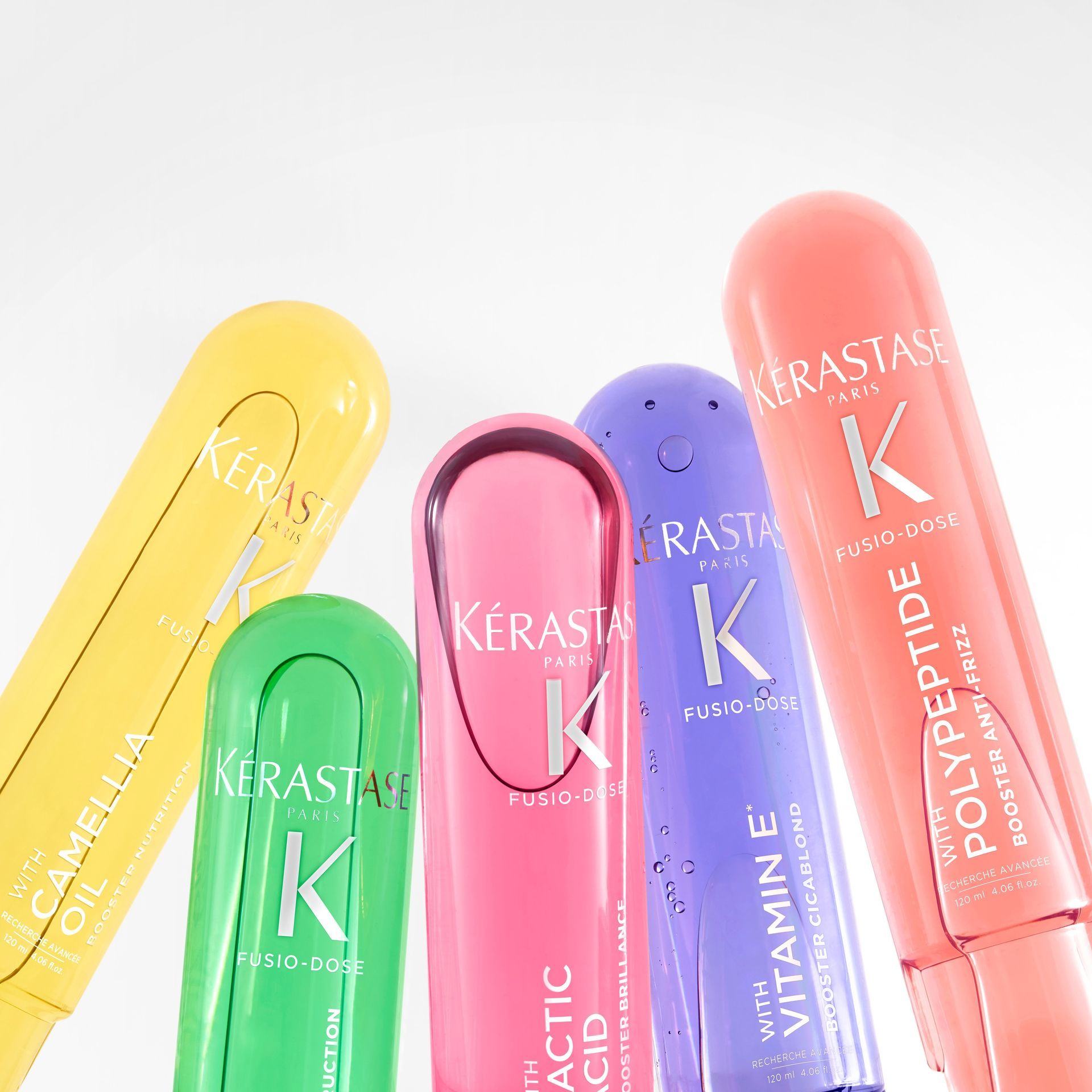 Several bottles of Kérastase products are lined up in a row