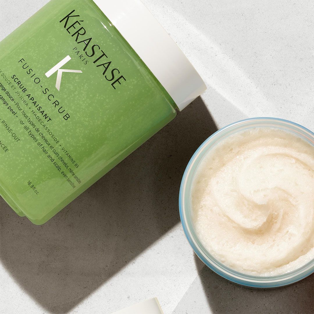 A bottle of Kérastase hair scrub next to a bowl of cream