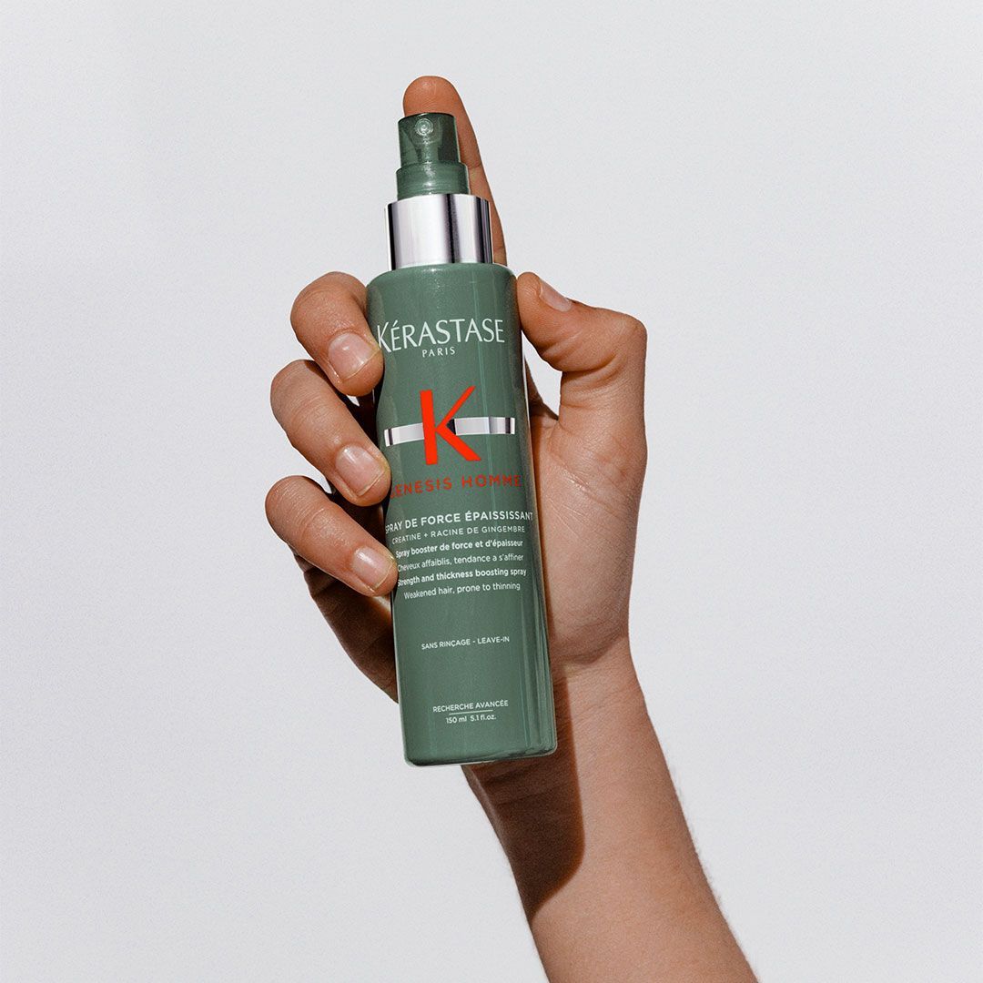 A person is holding a bottle of Kérastase spray in their hand