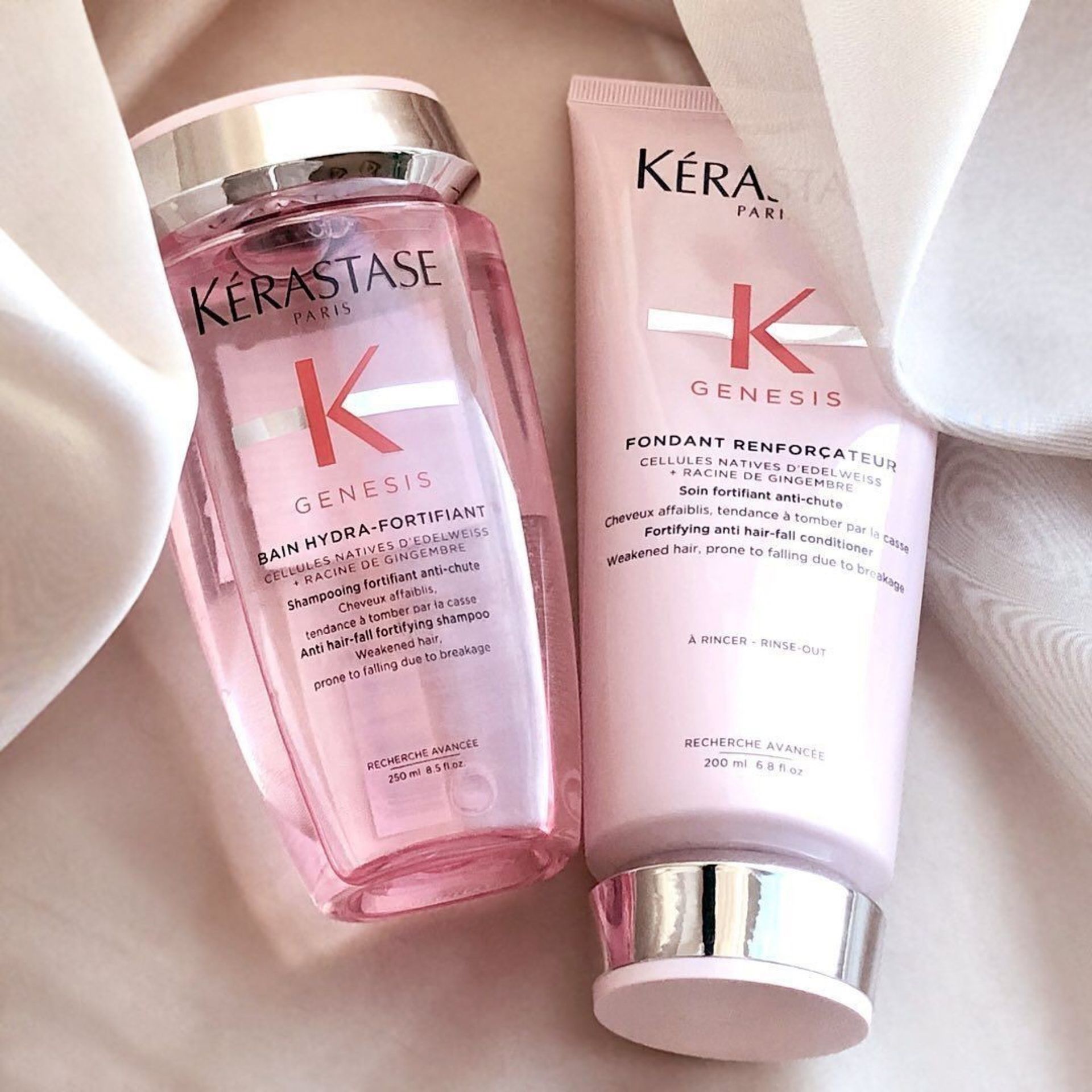 Two bottles of Kérastase shampoo and conditioner are sitting on a table