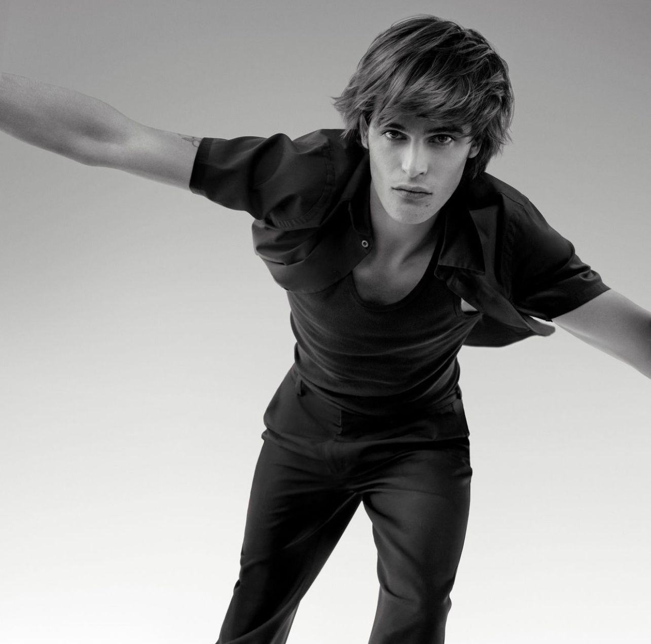 A black and white photo of a young man with his arms outstretched