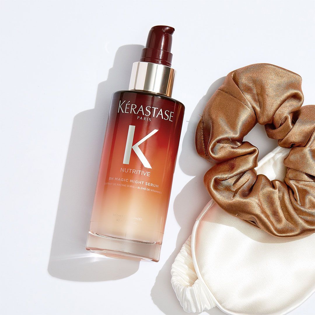 A bottle of Kérastase hair serum next to a scrunchie