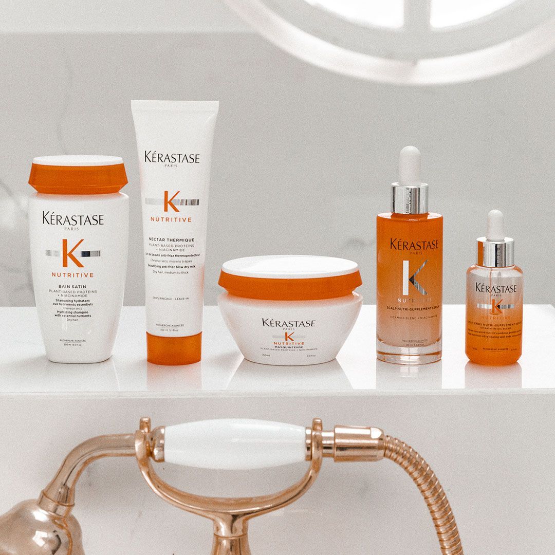 Several bottles of Kérastase products are on a bathroom counter