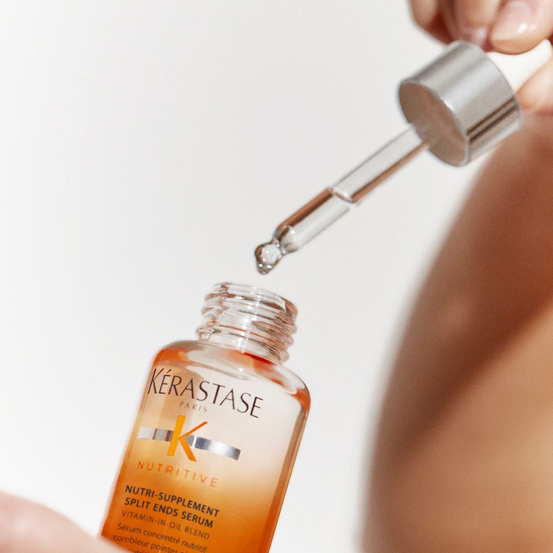 A person is holding a bottle of Kérastase hair serum