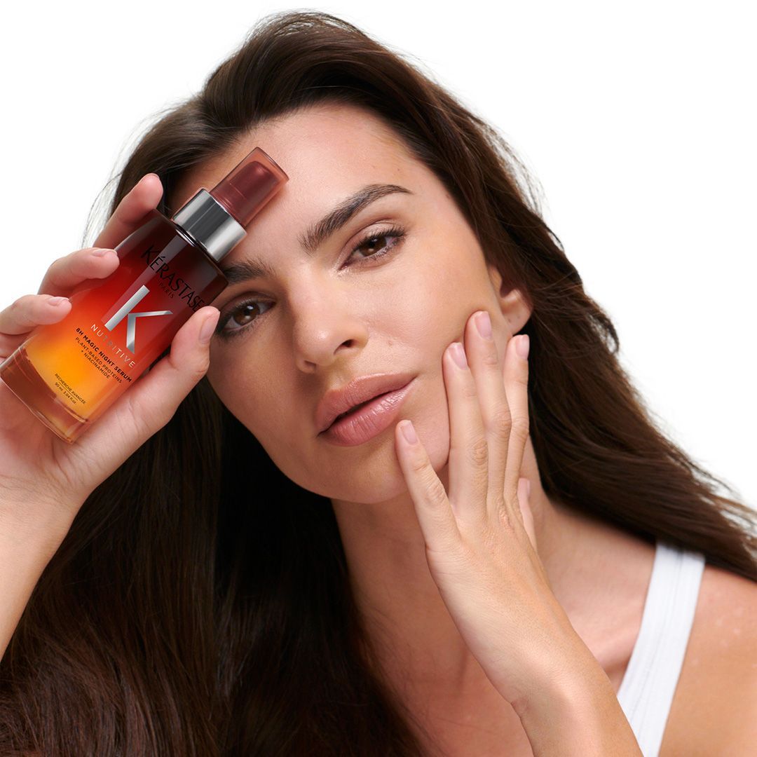 A woman is holding a bottle with the letter K on it