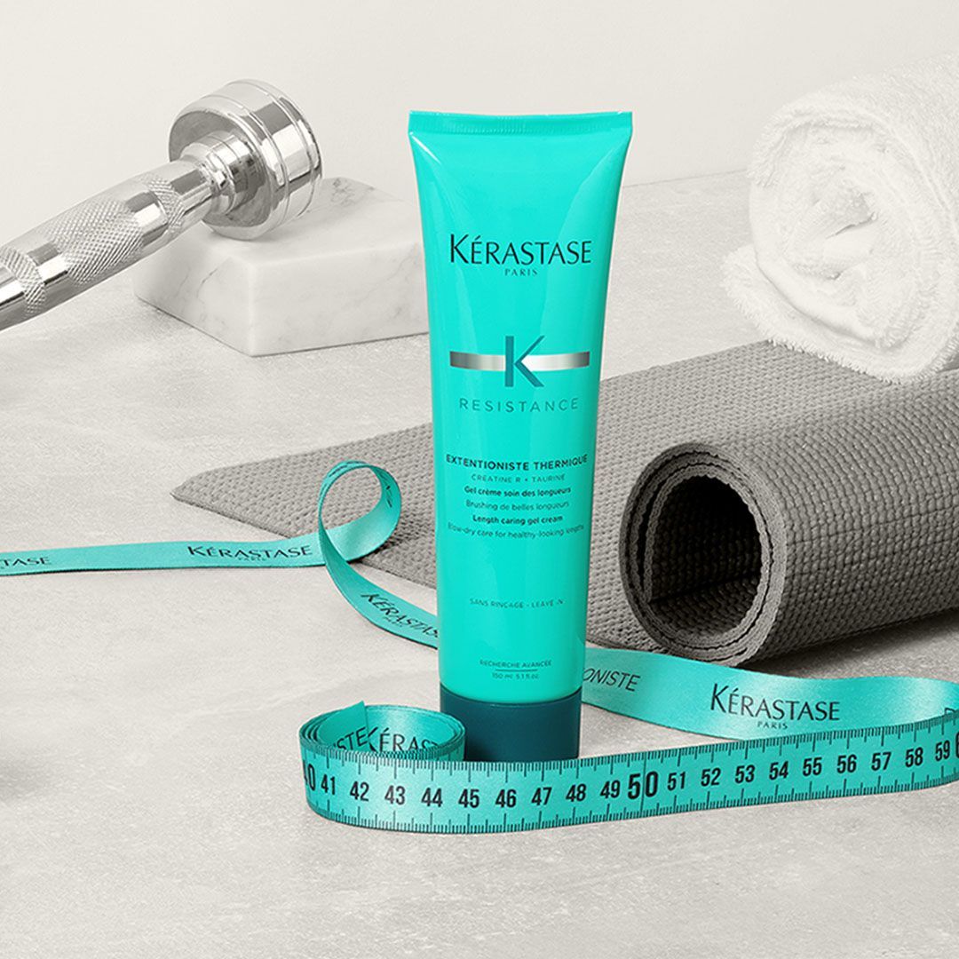 A bottle of Kérastase hair product is sitting next to a measuring tape