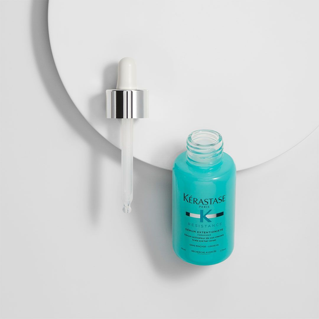 A bottle of Kérastase serum with a dropper on a white surface