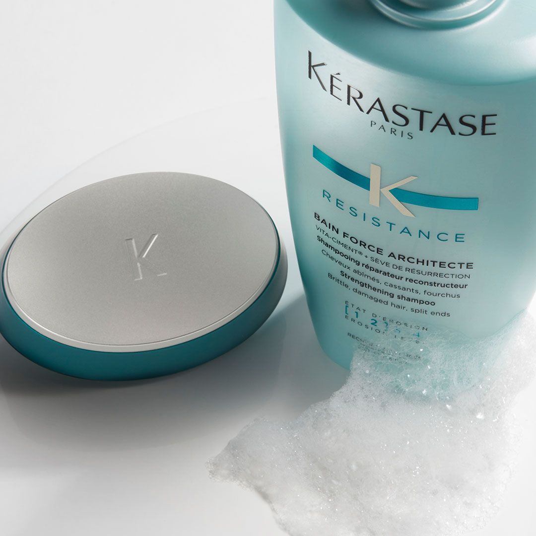 A bottle of Kérastase resistance shampoo next to a soap dish