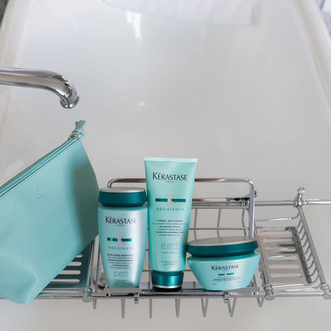 Bottles of Kérastase hair products are on a bathtub rack