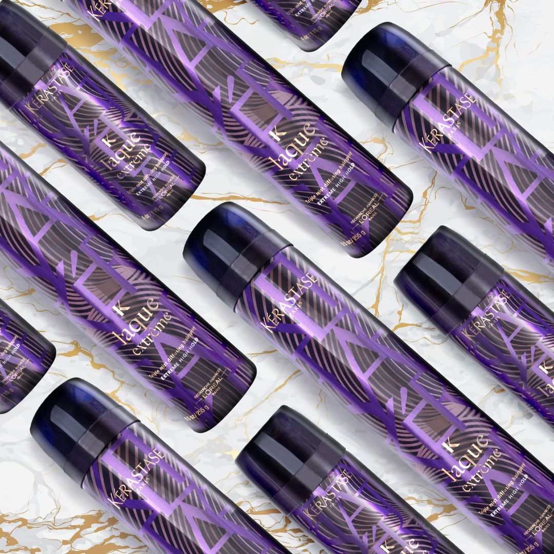 A bunch of purple spray bottles are lined up on a marble surface