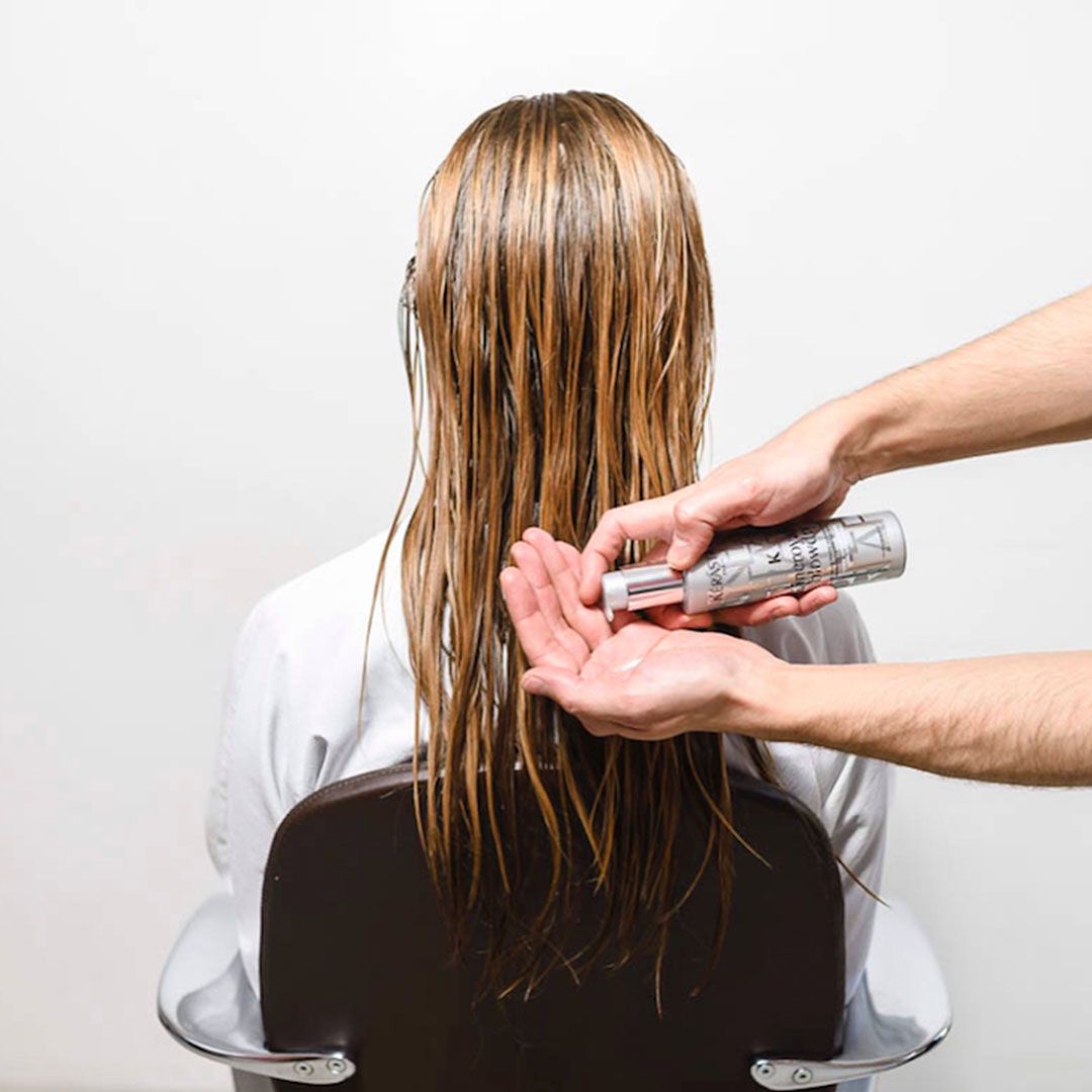 A woman is getting her hair dyed by a hairdresser
