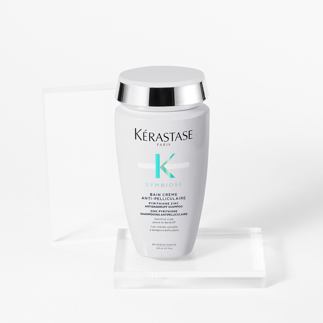 A bottle of Kérastase shampoo is sitting on top of a clear block