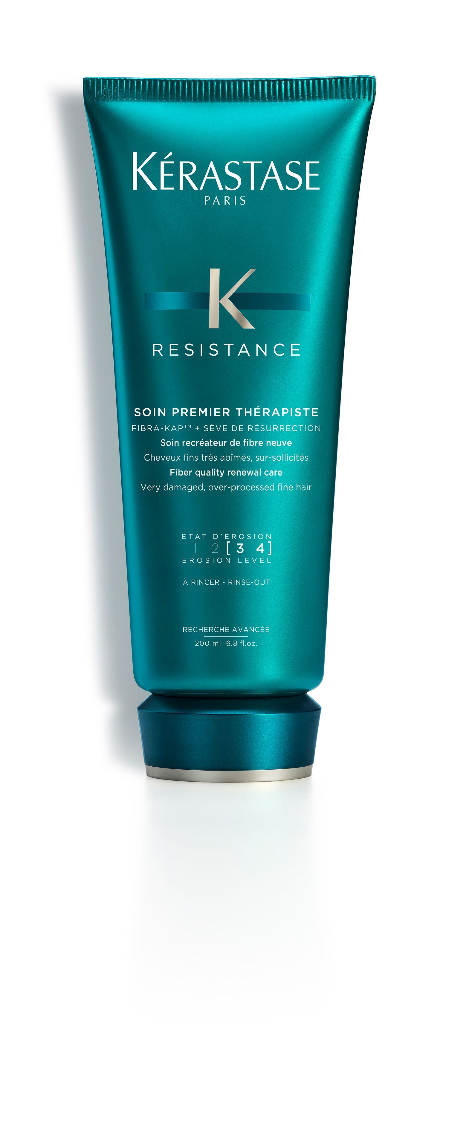 A bottle of Kérastase hair product is sitting on a white surface