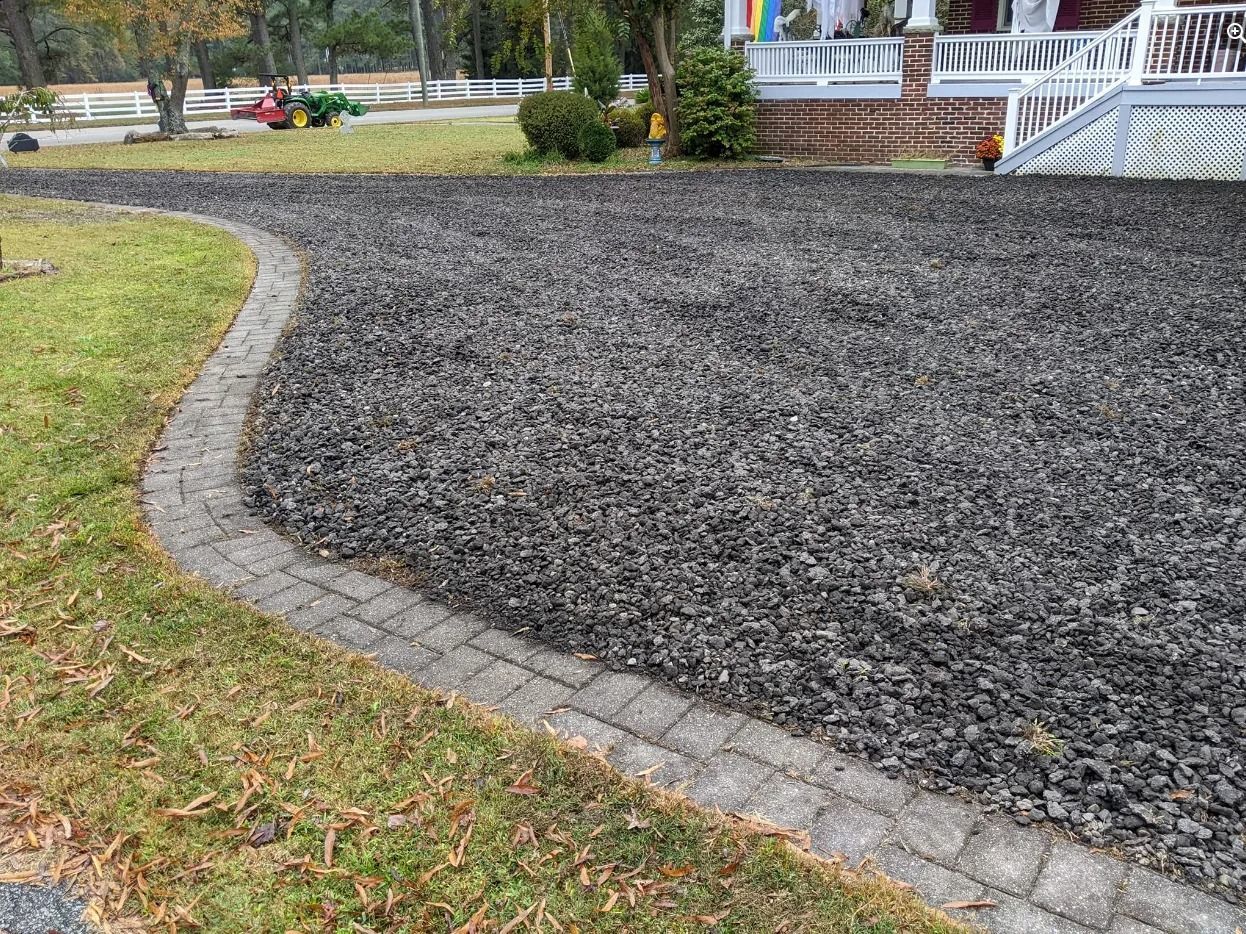 Curved stone border around a dark mulch bed beside a grassy park lawn