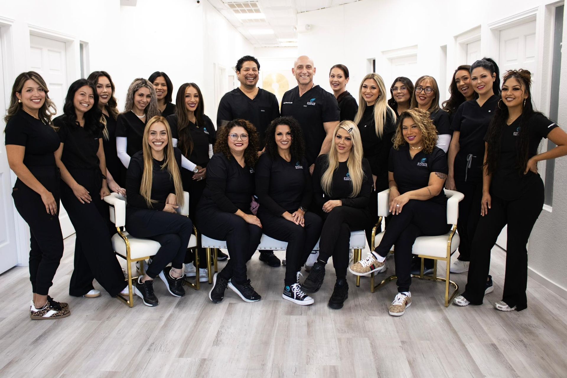Group of people in black scrubs posing in a white hallway.