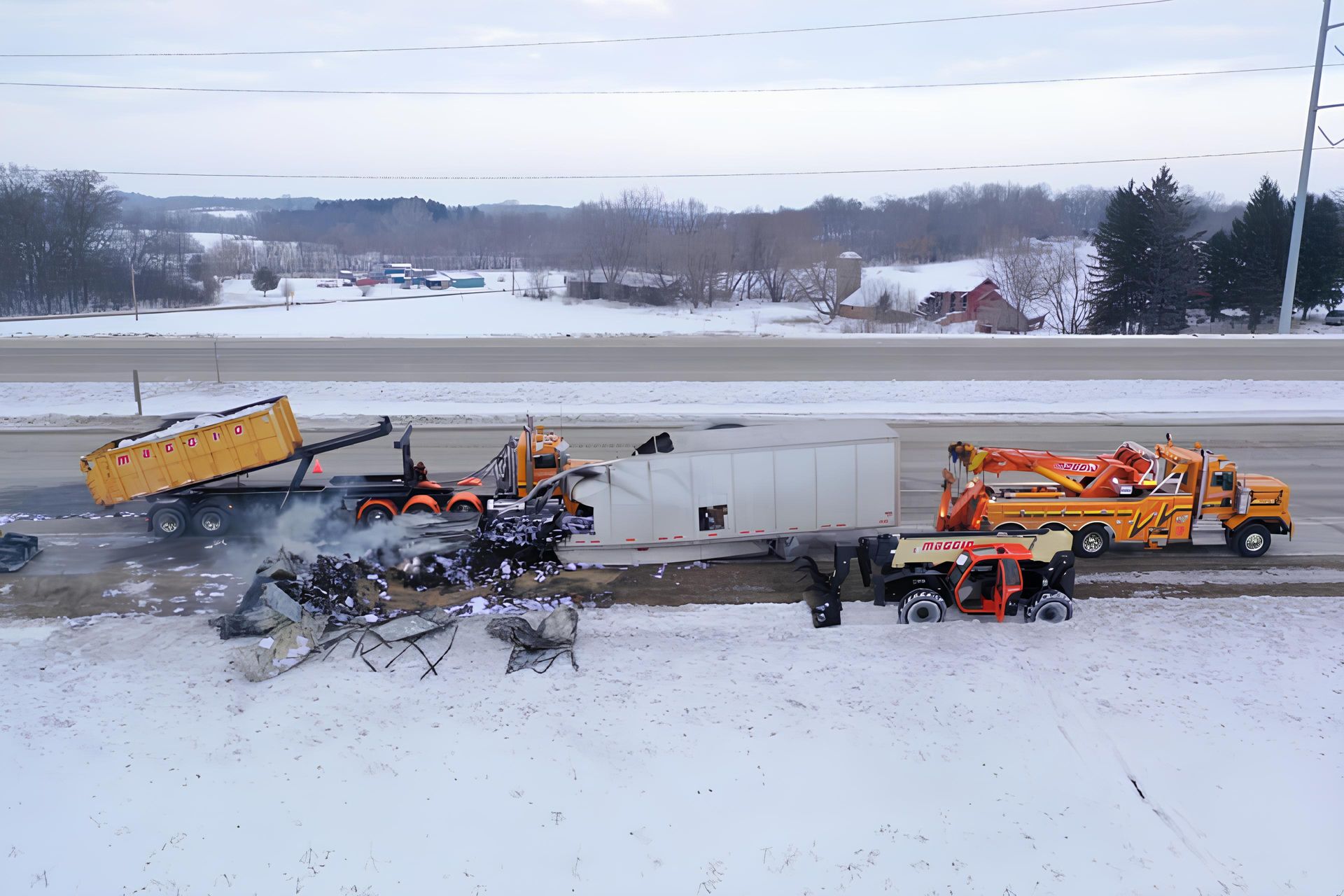 Semi-truck crash scene on snowy highway with tow trucks. Debris and smoke visible.