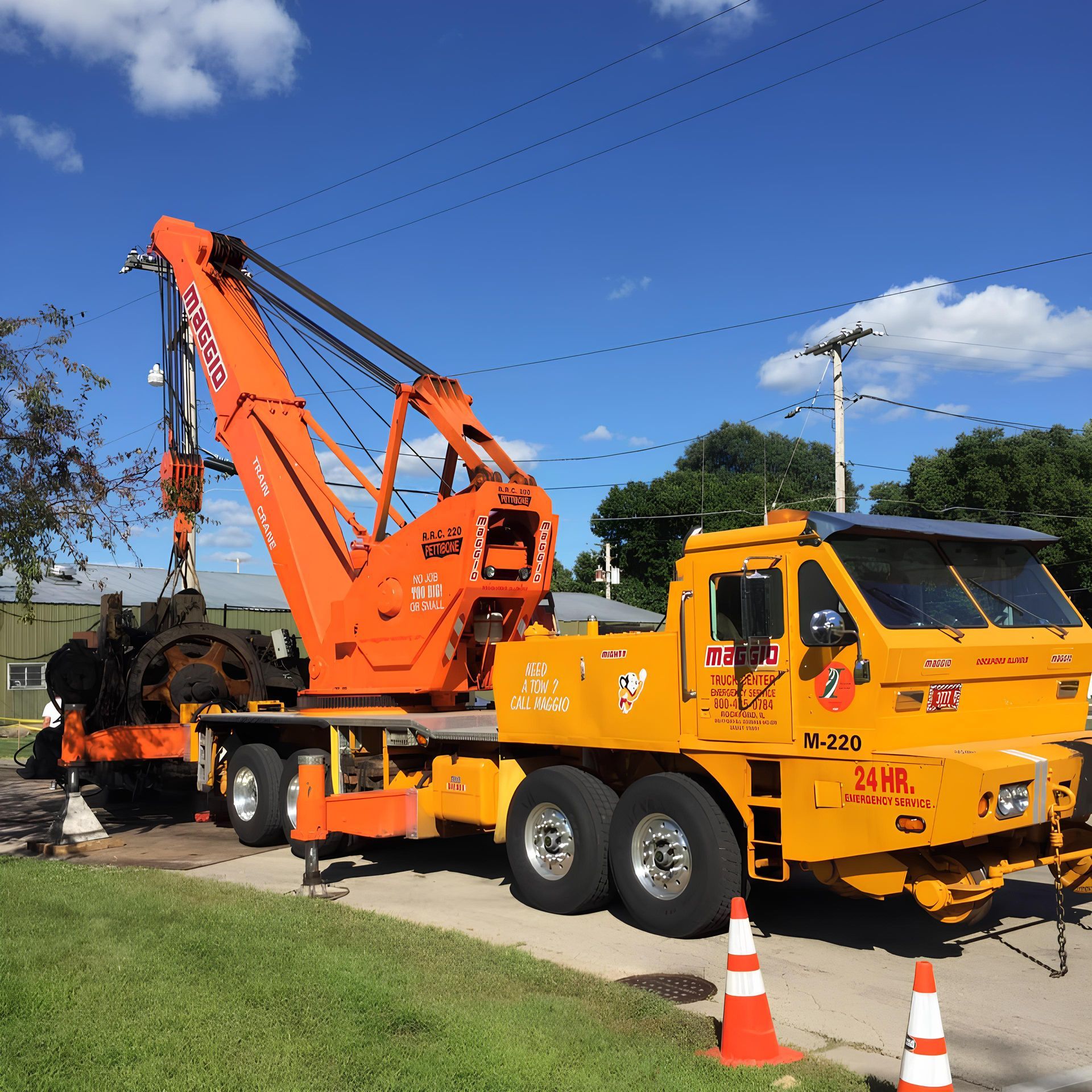 Orange crane truck parked on a street with its arm extended.