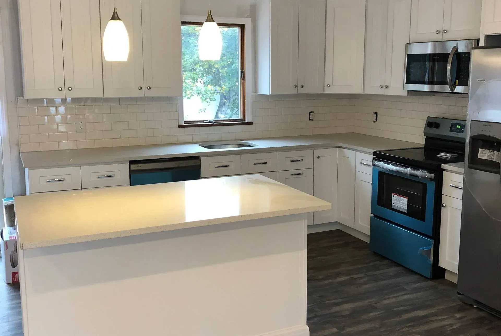 A kitchen with white cabinets, stainless steel appliances, and a large island.