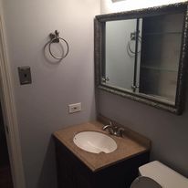 A bathroom with a sink , toilet , mirror and medicine cabinet.
