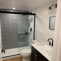 A bathroom with a toilet , sink , shower and bathtub.