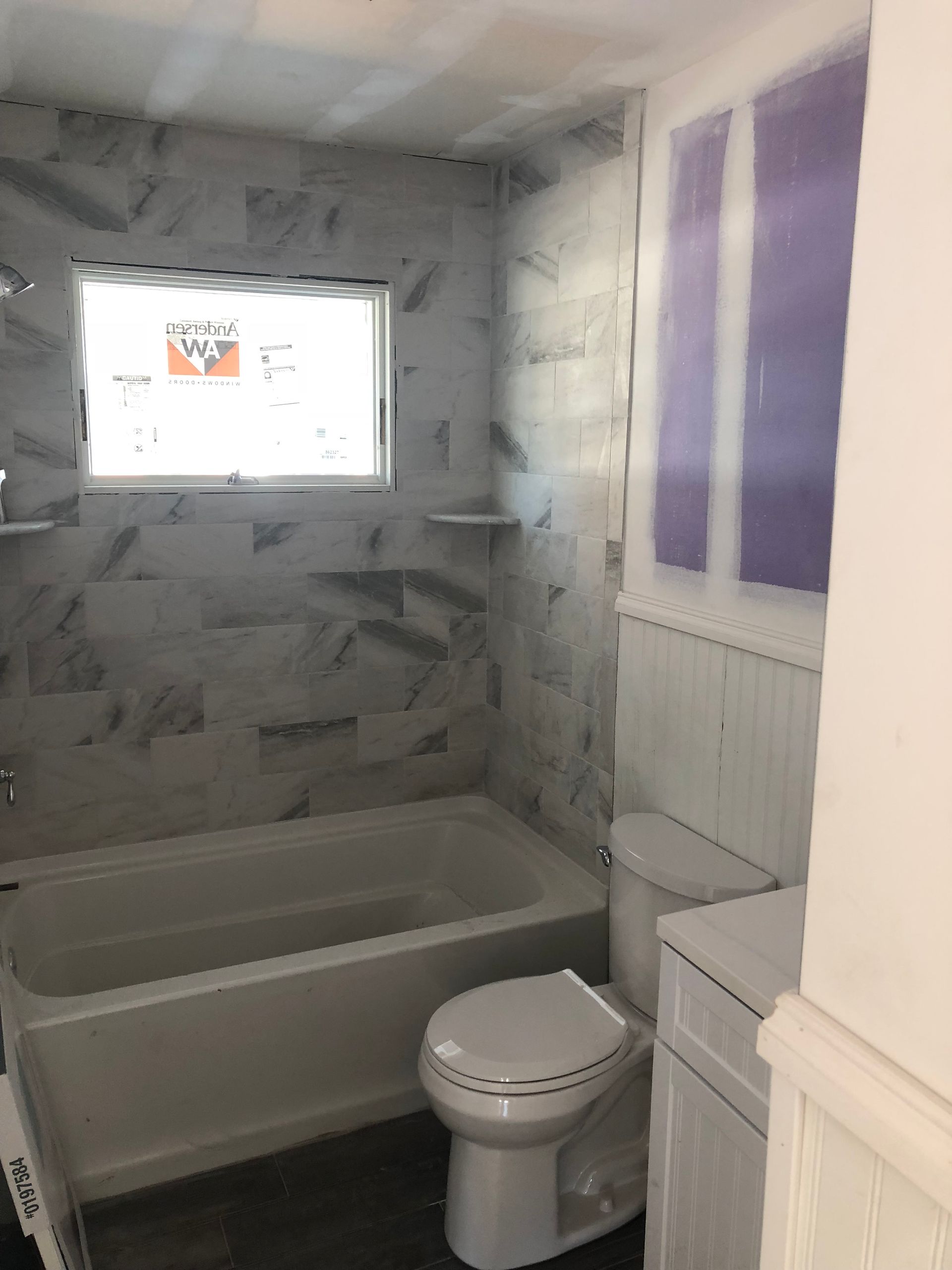 A bathroom with a toilet , bathtub and window.