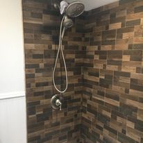 A shower with a brick wall and a shower head.