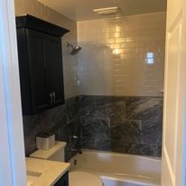 A bathroom with a tub , toilet , sink and shower.