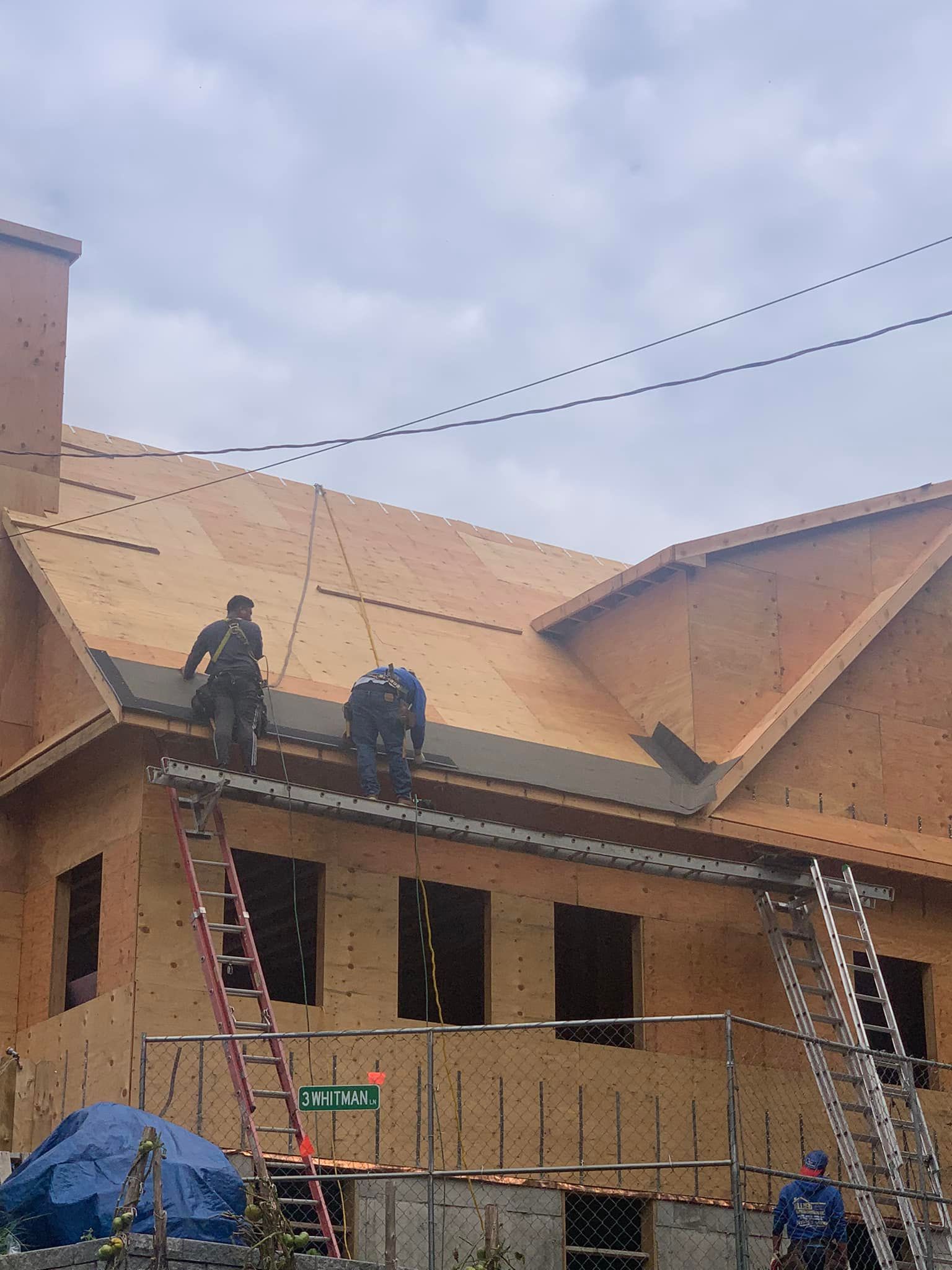 A group of construction workers are working on the roof of a house under construction.