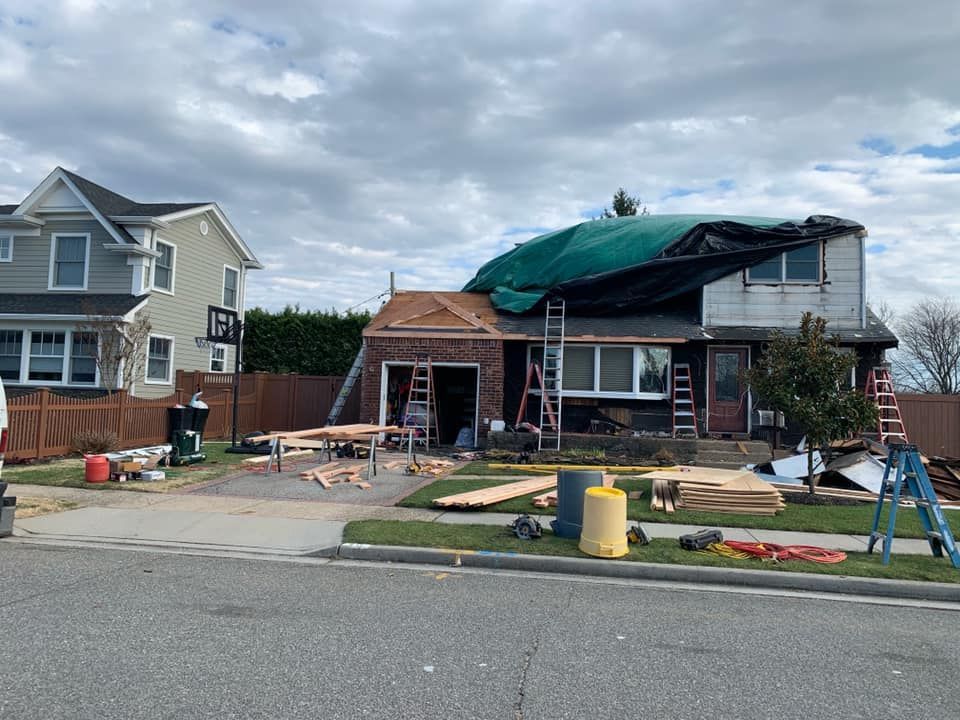 A house is being remodeled with a green tarp on the roof.