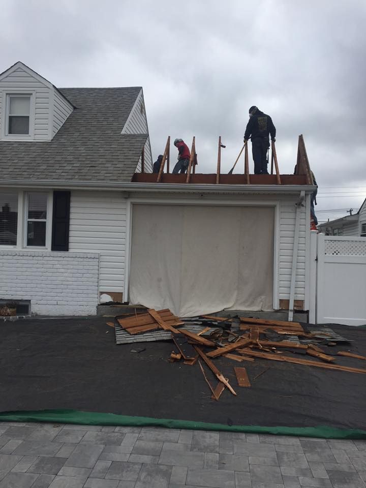 Two men are working on the roof of a white house