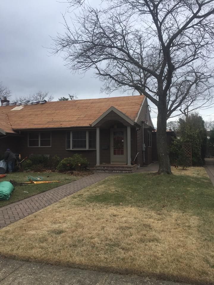 A brick house with a wooden roof and a tree in front of it.