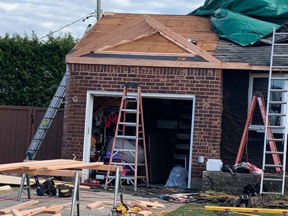 A brick garage is being remodeled with a wooden roof.