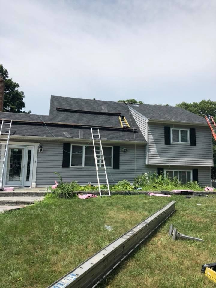 A house with a ladder on the roof is being remodeled.