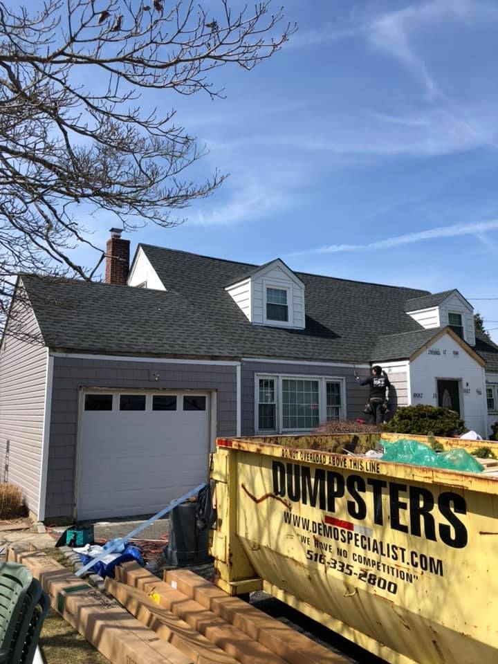 A yellow dumpster is parked in front of a house.