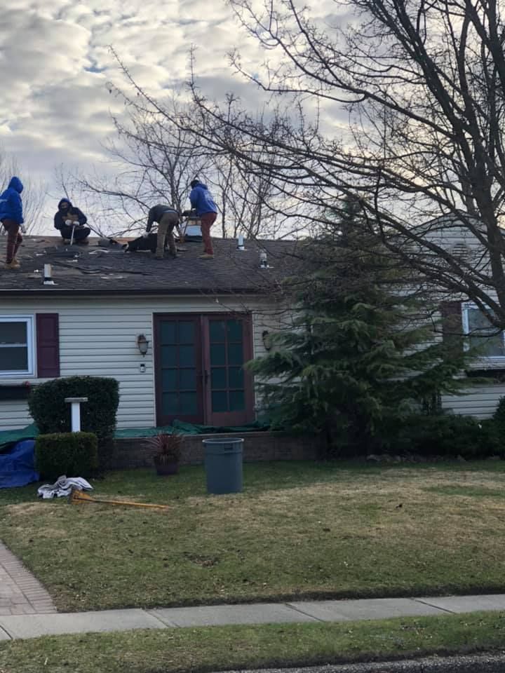 A group of people are working on the roof of a house.
