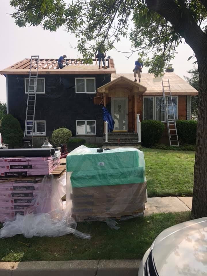 A group of people are working on the roof of a house.