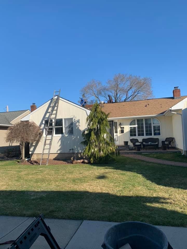 A white house with a brown roof and a ladder in front of it.