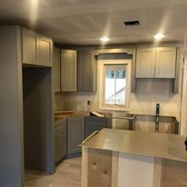 A kitchen with gray cabinets and stainless steel appliances is being remodeled.