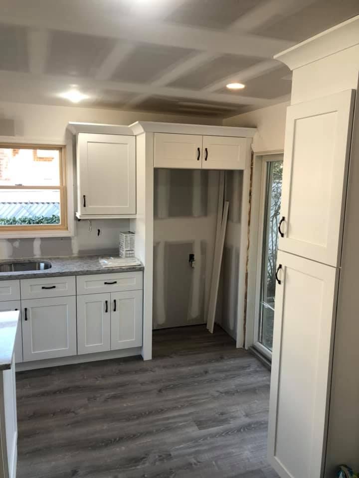 A kitchen with white cabinets and a sink under construction