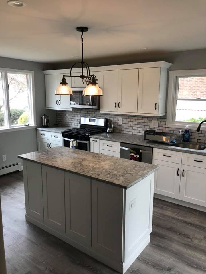 A kitchen with white cabinets , granite counter tops , stainless steel appliances and a large island.
