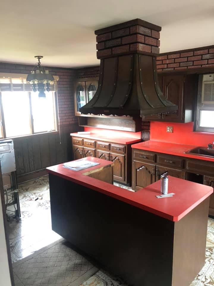 A kitchen with red counter tops and a brick chimney.