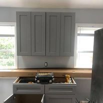 A kitchen with gray cabinets and a window.