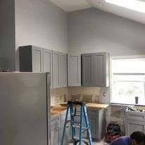A man is working in a kitchen with a ladder.
