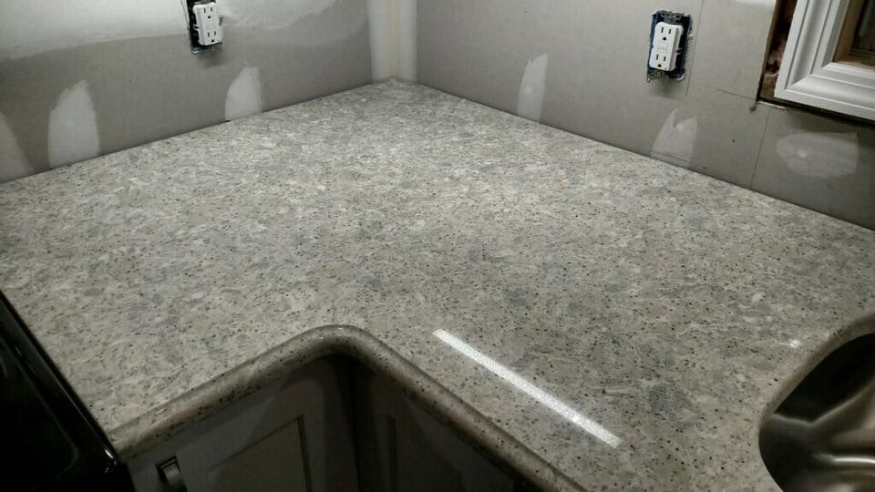 A kitchen with a granite counter top and a stainless steel sink.