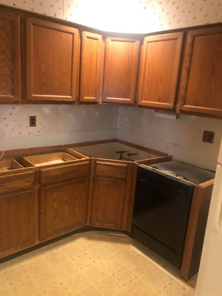 A kitchen with wooden cabinets and a black dishwasher.