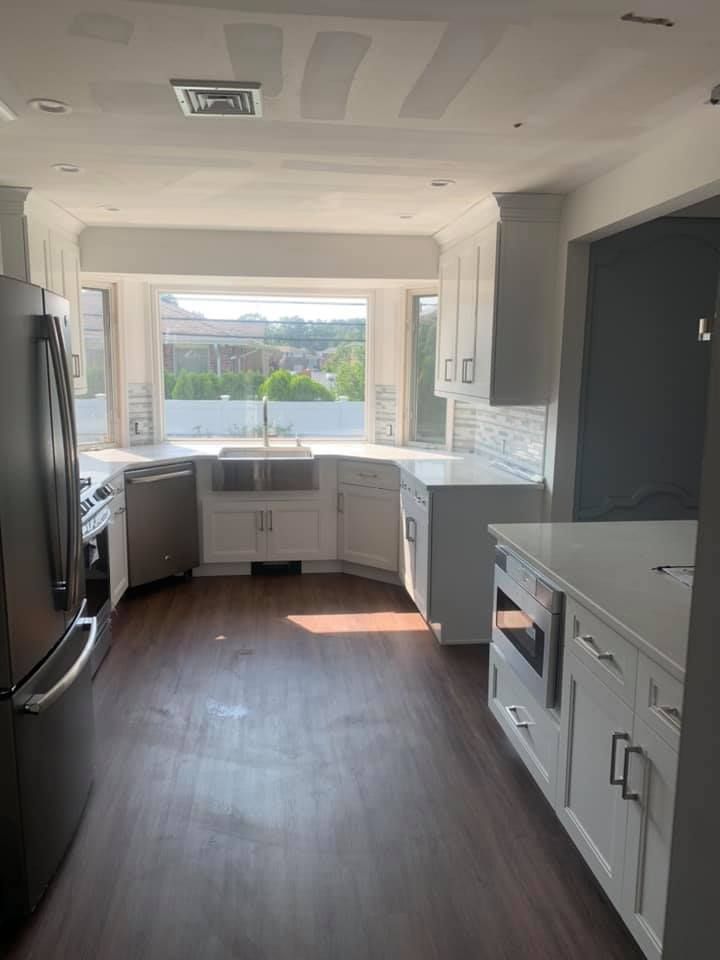 A kitchen with white cabinets , stainless steel appliances , and a large window.