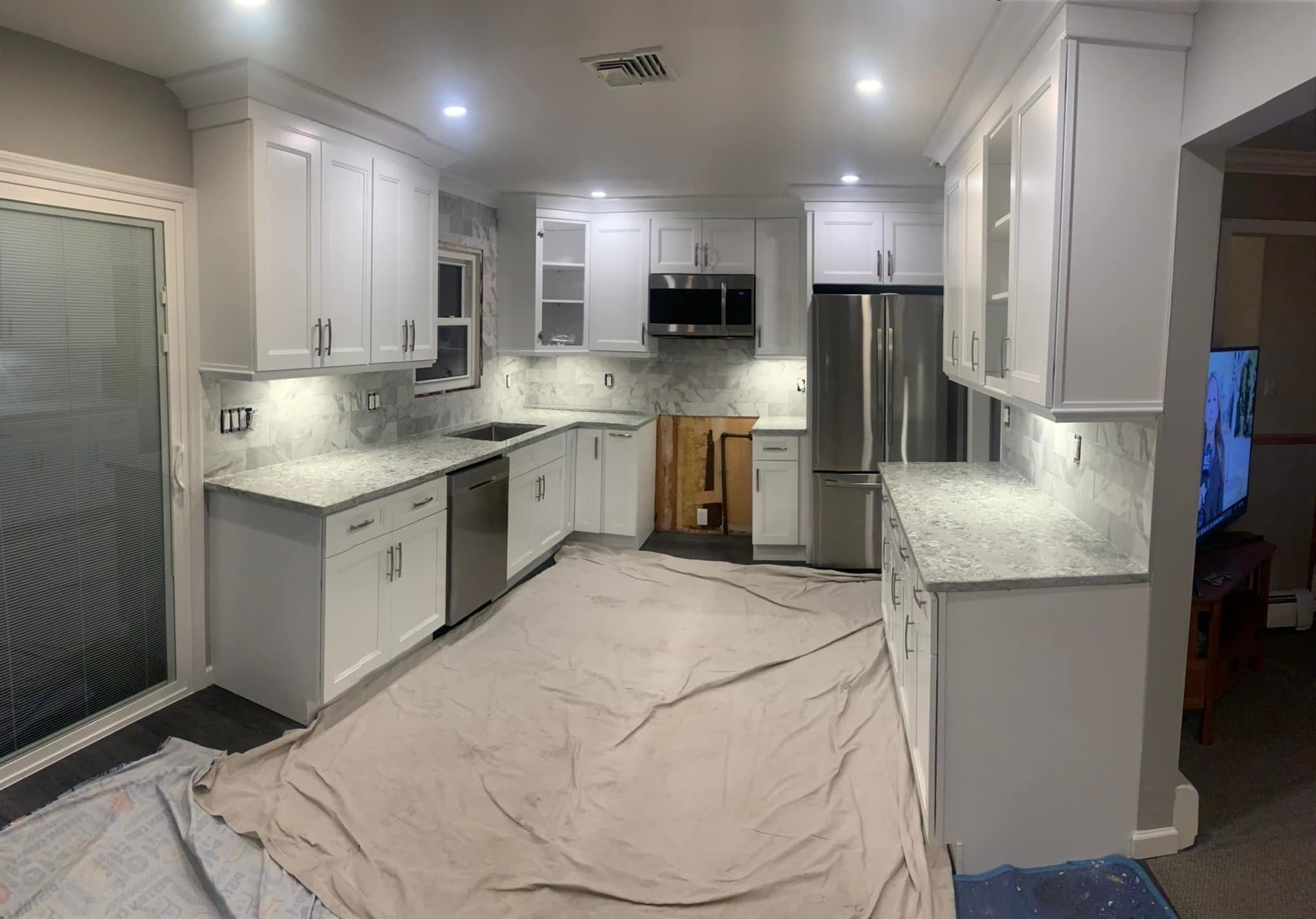 A kitchen with white cabinets and stainless steel appliances is being remodeled.